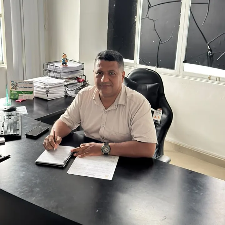 Integrante del equipo administrativo en su escritorio, tomando notas en una libreta.